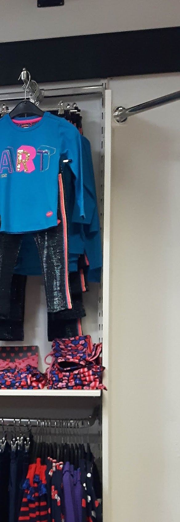 Een rek met kindershirts en broeken